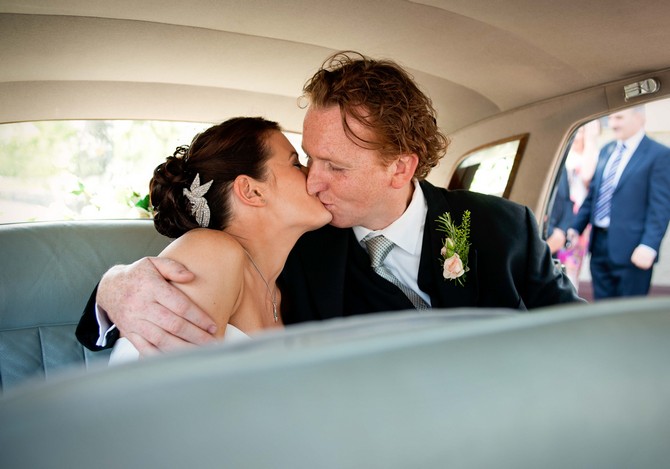 kissing couple bride and groom in blue wedding car. Tara Aherne Photography bride and groom kiss in car